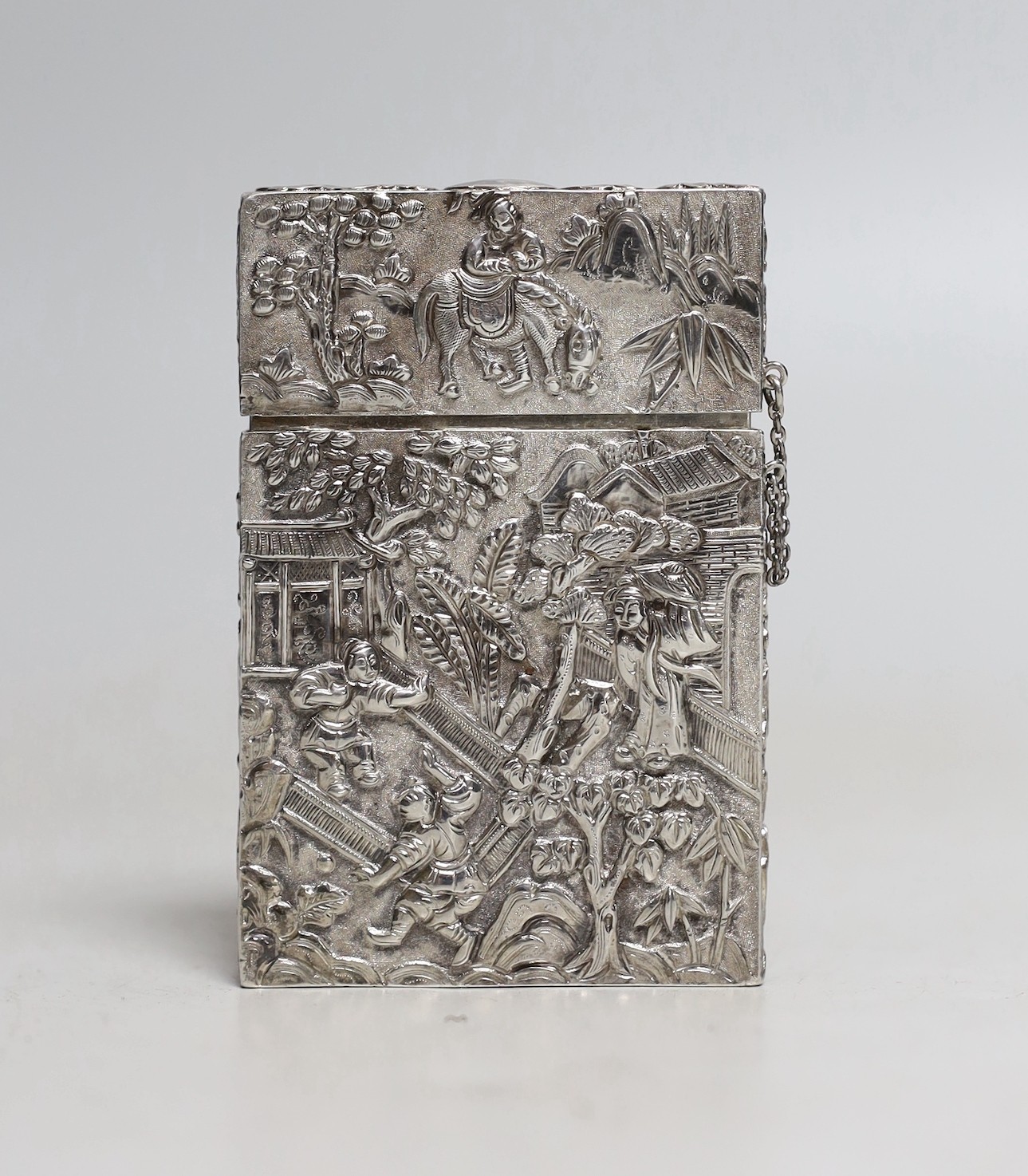 A 19th Chinese Export white metal rectangular card case, by Cutshing, stamped 'CUT', embossed with figured in garden scene and prunus tree, 78mm.